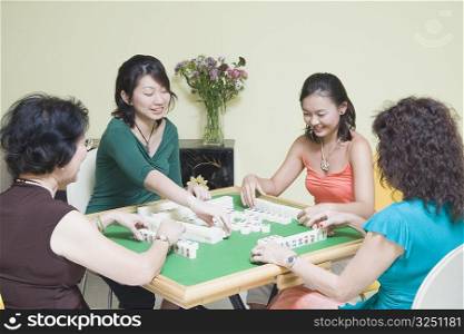 Four women playing with blocks at a table and smiling