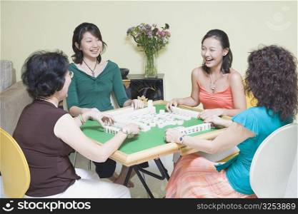Four women playing with blocks at a table and smiling