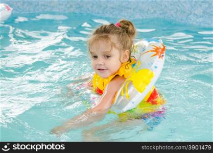 Four-year girl floating in the pool. Six year old girl Europeans bathed in a small suburban pool