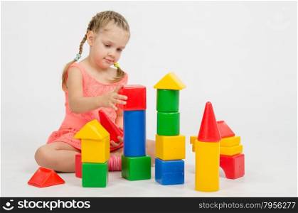 Four-year girl playing in a European-style cubes, isolated on a light background
