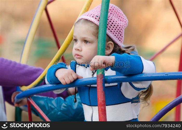 Four-year girl playing on the playground in the cool spring weather. Four-year girl thought playing on the playground