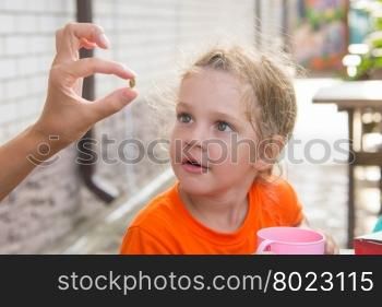 Four-year girl showing a pea, which she treats with great interest
