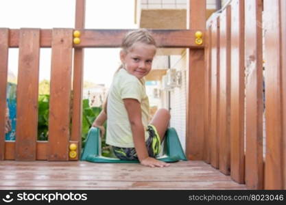 Four-year girl sitting on a wooden platform personal game complex