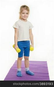 Four-year girl standing with dumbbells. Four-year girl Europeans engaged in physical exercises