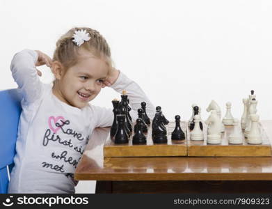 Four-year-old girl playing in chess. Girl fun looking at the Board,preparing to make the next move