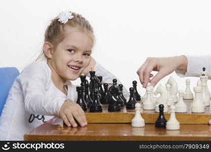 Four-year-old girl playing in chess. Girl fun looking at the Board,preparing to make the next move