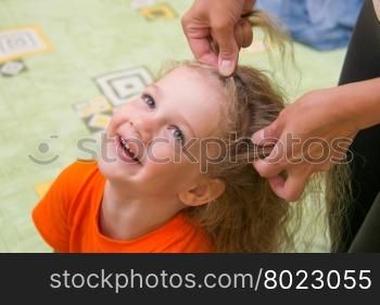 four years old girl laughs as she braided long hair