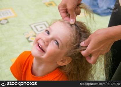 four years old girl laughs as she braided long hair