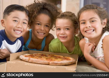 Four young children indoors with pizza smiling