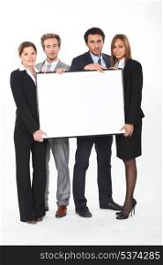 Four young executives holding a framed board left blank for your image