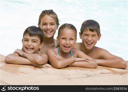 Four young friends in swimming pool smiling