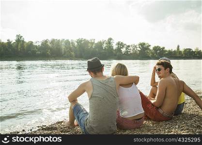 Four young friends sitting on lakeshore