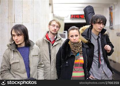 Four young musicians at metro station, focus on girl