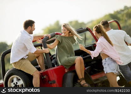 Four young people having fun in convertible car by river