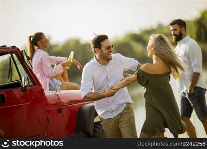 Four young people having fun in convertible car by river
