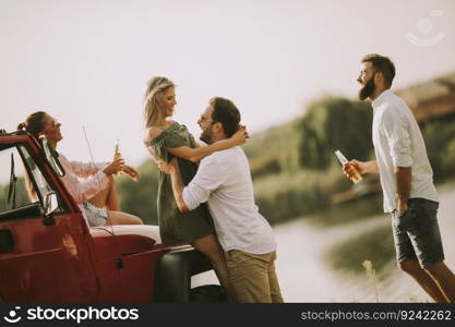 Four young people having fun in convertible car by river