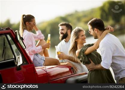 Four young people having fun in convertible car by river