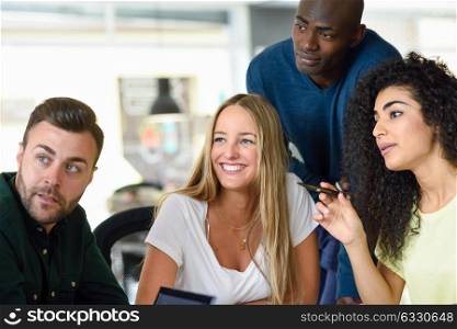 Four young people working together. Beautiful men and women in a business meeting wearing casual clothes. Multi-ethnic group.