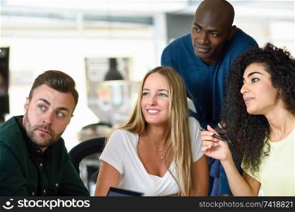 Four young people working together. Beautiful men and women in a business meeting wearing casual clothes. Multi-ethnic group.. Beautiful men and women working toghether wearing casual clothes.