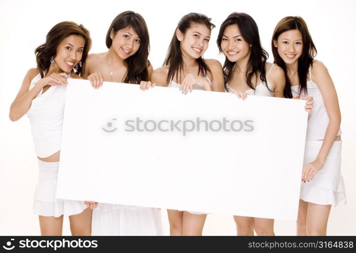 Four young women and a teenage girl holding a blank placard and smiling