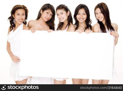 Four young women and a teenage girl holding a blank placard and smiling