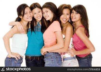 Four young women and a teenage girl standing together and smiling