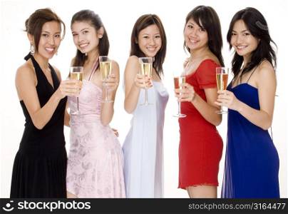 Four young women and a teenage girl toasting with champagne flutes and smiling