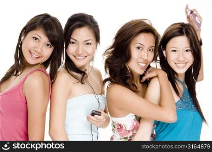 Four young women listening to MP3 players and smiling