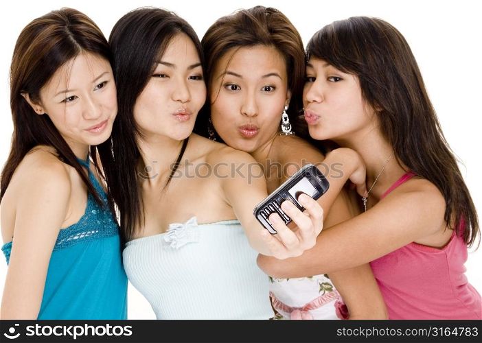 Four young women taking a picture of themselves with a mobile phone