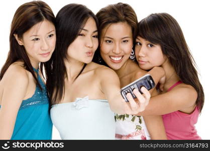 Four young women taking a picture of themselves with a mobile phone