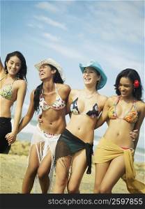Four young women walking together on the beach