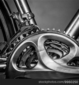 Fragment of a frame and parts of a road bike. The frame is made of titanium and there are several details to see  here is the wheel with spokes and , the gears