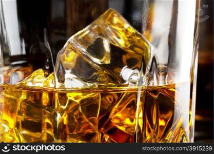 Fragment of a glass of whiskey with ice on a black background