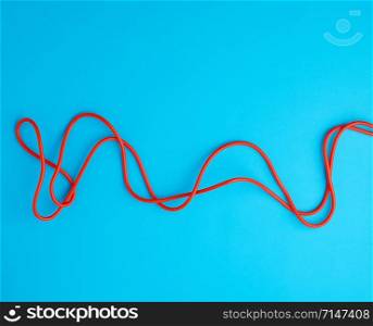 fragment of a red jump rope for sports on a blue background, two lines