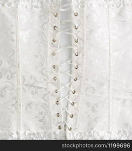 fragment of a white satin corset with lacing, back view, clothing item for brides, close up