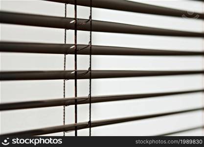 Fragment of brown horizontal blinds, close-up in selective focus. Office or home blinds. Lighting range control for office and meeting rooms