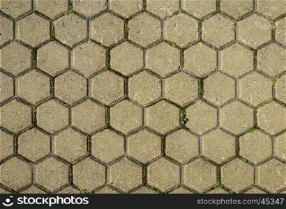 Fragment of gray tiled pavement texture with green grass
