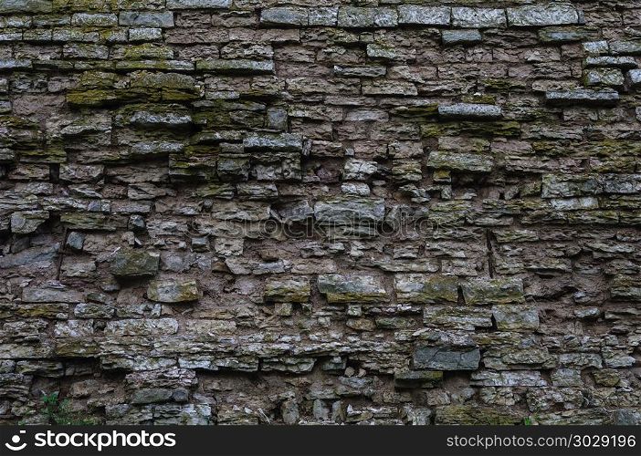 Fragment of old destroyed gray limestone brick wall surface. Rough weathered limestone wall