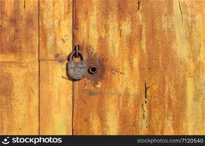 Fragment of old rusty metal garage gate with padlock