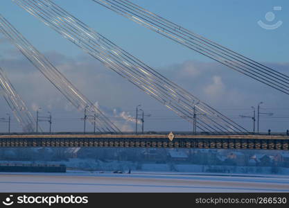 Fragment of Suspension bridge in winter. Vansu bridge over the frozen river Daugava in Riga.