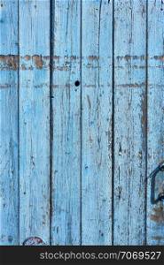 fragment of very old wooden door with blue cracked paint, parallel boards, full frame