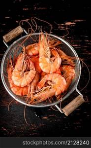 Fragrant boiled shrimp in a colander. On a rustic dark background. High quality photo. Fragrant boiled shrimp in a colander.