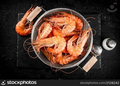 Fragrant boiled shrimp in a colander. On a rustic dark background. High quality photo. Fragrant boiled shrimp in a colander.