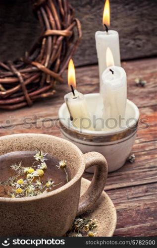 fragrant chamomile tea and burning candles in rustic style.Selective focus. healing with chamomile broth