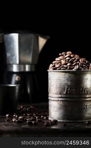 Fragrant coffee beans in a metal vintage mug, a coffee pot and a cup of coffee on the table in the background, the idea of making coffee