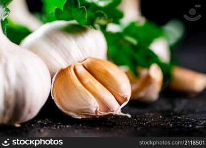 Fragrant garlic with parsley on the table. On a black background. High quality photo. Fragrant garlic with parsley on the table.