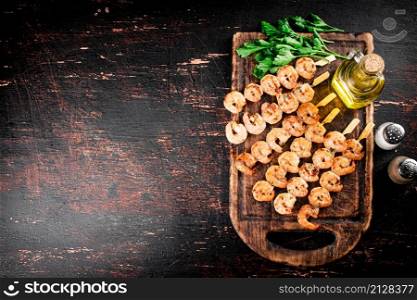 Fragrant grilled shrimp on a cutting board with oil and parsley. Against a dark background. High quality photo. Fragrant grilled shrimp on a cutting board with oil and parsley.