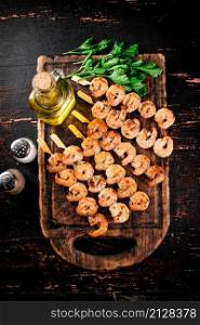 Fragrant grilled shrimp on a cutting board with oil and parsley. Against a dark background. High quality photo. Fragrant grilled shrimp on a cutting board with oil and parsley.