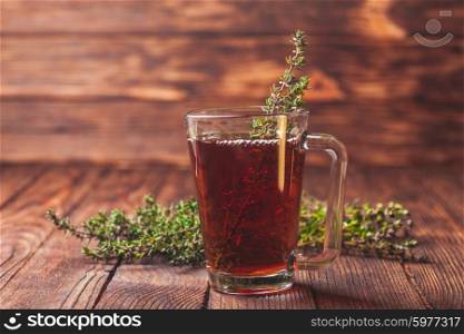 Fragrant herbal tea with bunches thyme in a glass mug. The thyme tea