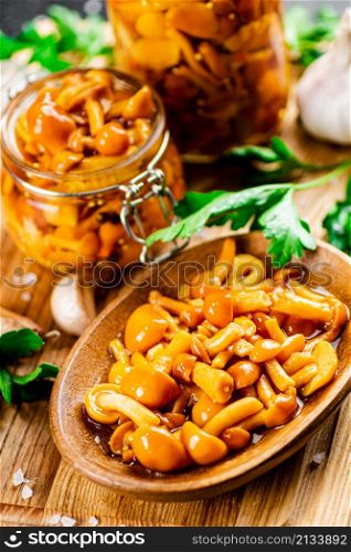 Fragrant marinated mushrooms with parsley. On a wooden background. High quality photo. Fragrant marinated mushrooms with parsley.